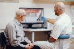 a dentist reviewing an elderly man's dental report